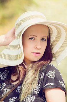 Cheerful fashionable woman in stylish hat and frock posing outdoor. Happy brunette girl with long hair in warm spring day