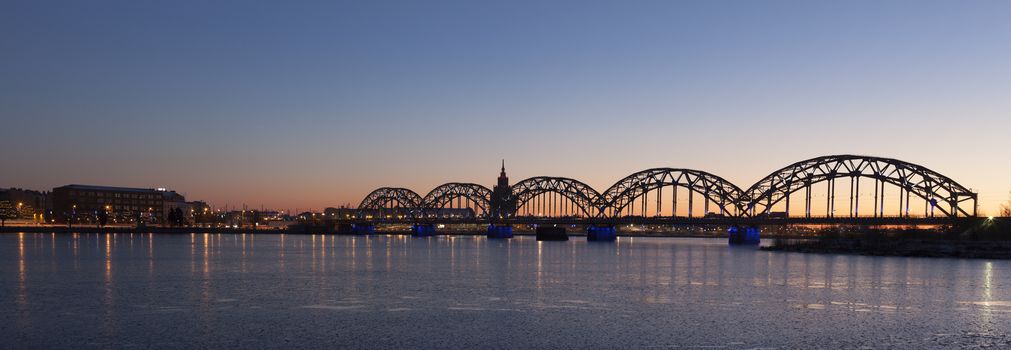 Panorama shot of Riga Railway Bridge over river Daugava during dawn time