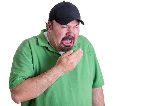 Upper Body Image of Overweight Man Wearing Green Shirt and Black Baseball Cap Covering Mouth While Sneezing in front of White Background
