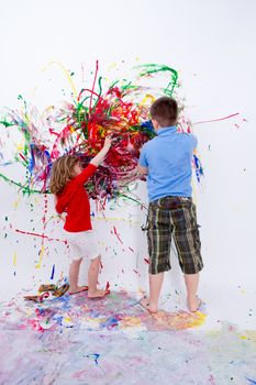 Two Siblings Painting Contemporary Art on White Big Wall Using Colorful Paints During their Bonding Time.