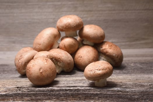 Fresh brown champignons on wooden background