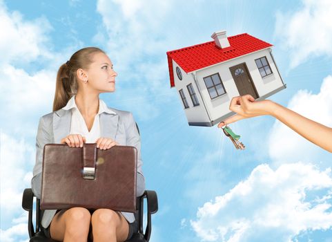 Businesswoman sitting in the chair and looking to the right at womans hand offering house and keys