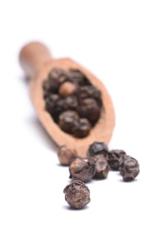 black peppercorns on a wooden scoop isolated on white