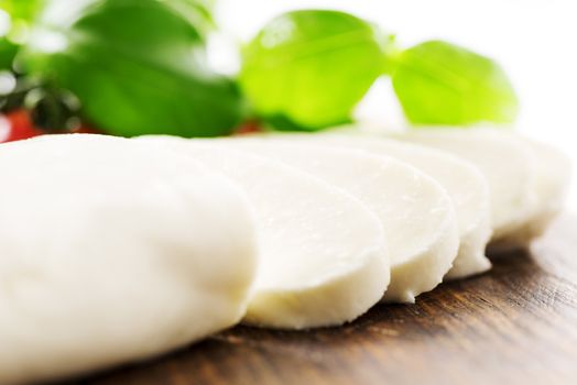 Ingredients for Caprese salad with mozzarella, tomato, basil and balsamic vinegar arranged on wooden table