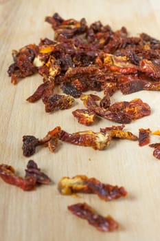 Sun dried tomatoes sliced up on a wooden cutting board.