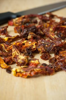 Sun dried tomatoes sliced up on a wooden cutting board.