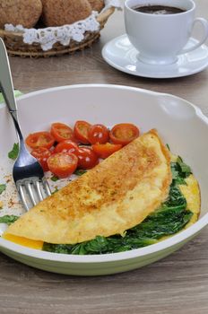 Omelet with spinach  and roasted tomatoes in a pan
