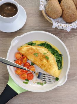 Omelet with spinach, cheese and roasted tomatoes in a pan