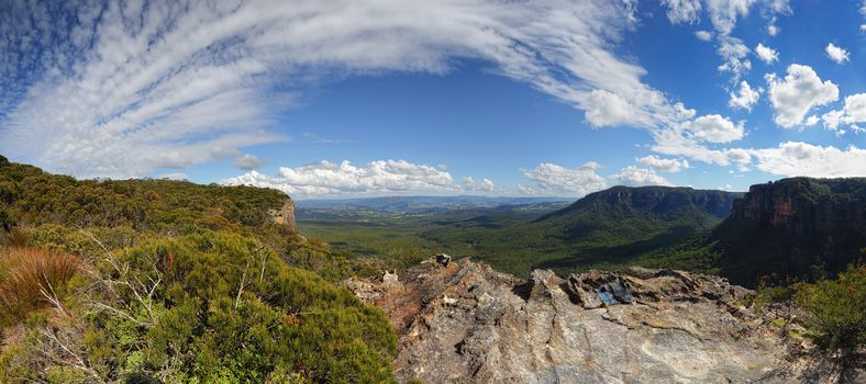 An extended view panorama as pretty clouds sweep across the sky in the Blue Mountains, views from Narrowneck escarpment  into Nellies Glen and the Megalong Valley.   This glorious day and these beautiful clouds hours later transformed into  rain, heavy hail and lightening storm.