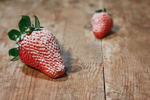 Red strawberries sprinkled with sugar on a wooden table