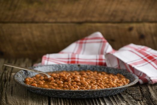 Plate of beans with pork in a rustic setting.