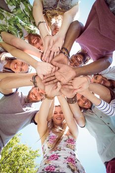 Happy young friends putting hands together on a summers day