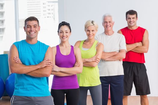 Portrait of happy men and women standing arms crossed at fitness studio