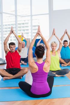 Female instructor with class practicing yoga in fitness club