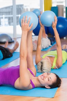Portrait of happy woman exercising with medicine ball in fitness club