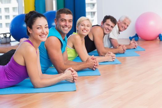 Portrait of happy people relaxing on exercise mats in fitness studio