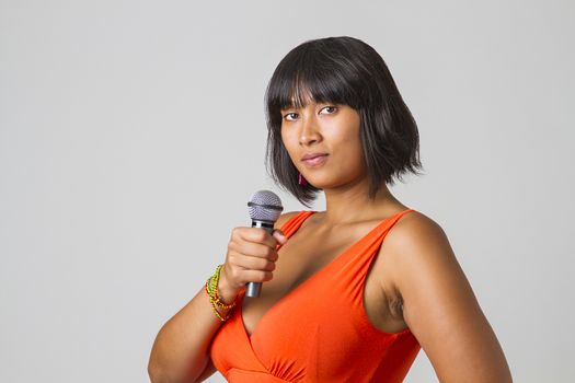 Young filipino woman wearing a low cut orange holding a microphone