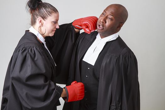 caucasian woman wearing a lawyer toga punching a black man wearing a lawyer toga
