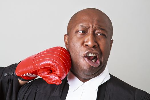 bald black man wearing canadian lawyer toga getting punch in the face by a red boxing glove