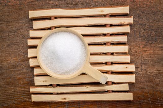 Epsom salts (Magnesium sulfate) in a rustic wooden scoop - relaxing bath concept