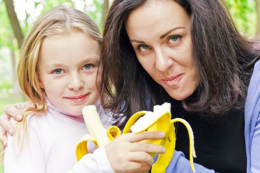 Photo of mother and daughter eating banana