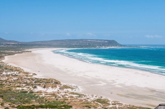 Two horse riders on Noordhoek Beach with the Kakapo shipwreck, Kommetjie and the Slangkop Lighthouse in the back