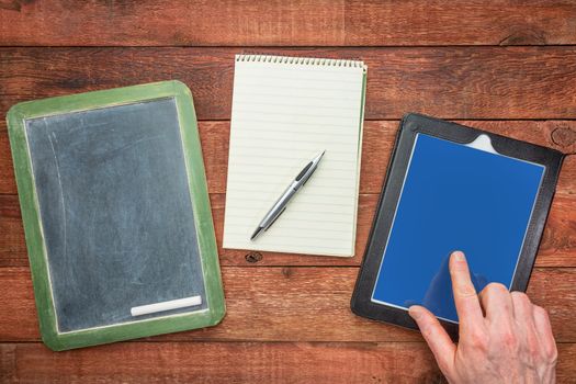 slate blackboard, with chalk, notepad with a pen and digital tablet with a finger - generations of making notes concept