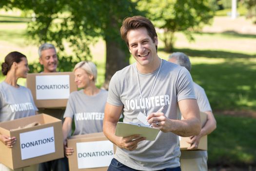 Happy volunteer man writing in clipboard on a sunny day