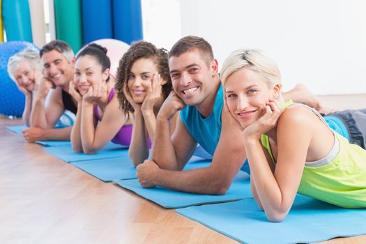 Portrait of fit people relaxing on exercise mats at fitness studio