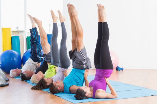 Full length of men and women working out in an fitness class