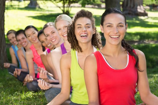 Fitness group doing yoga in park on a sunny day