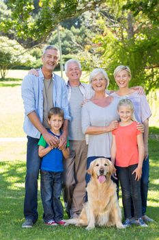 Happy family with their dog smiling to camera on a sunny day