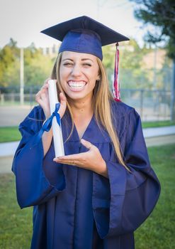Excited and Expressive Young Woman Holding Diploma in Cap and Gown Outdoors.