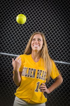 Young Female Softball Player Portrait with Ball in the Air.