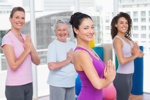 Side view portrait of female friends with hands clasped standing in gym