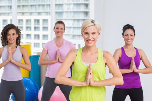 Portrait of happy fit women with hands joined exercising at gym