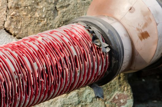 Old red pipe with black tape connection on grate.