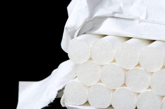 Lot of white cigarets in paper box isolated on black background.