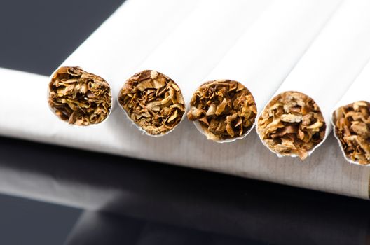 Lot of white cigarets in paper box isolated on black background.