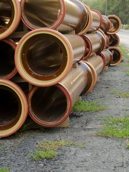 Stack of brown water pipes on the road. 