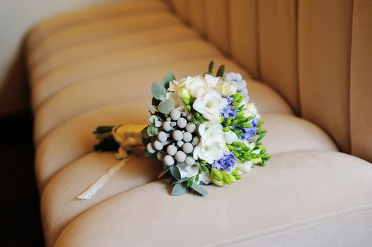 Wedding bouquet of white flowers lying on the sofa.
