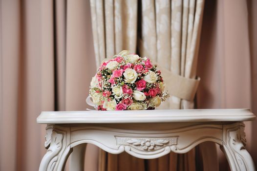 Wedding bouquet of bride - colorful flowers pink, white roses lying on table at wedding