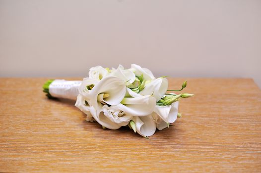 Wedding bouquet of bride lying on table. White flowers