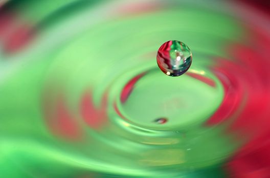 Falling water drop and nice splash on colorful background. 