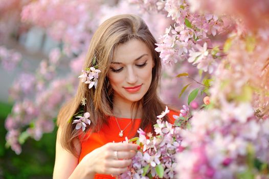 beautiful young brunette woman standing near the apple tree.