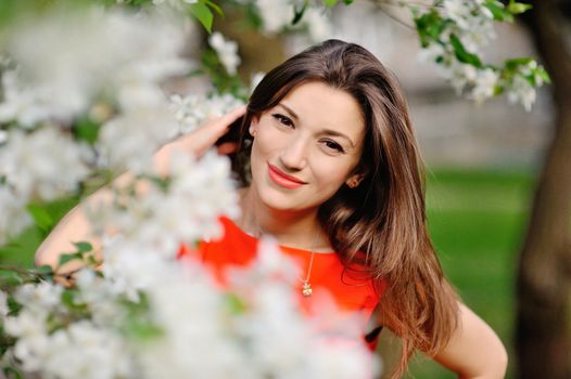 Portrait of pretty girl near the blossomed tree in the park. Concept of youth and natural beauty