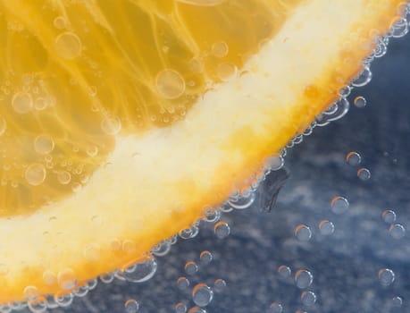 Orange in water on blue background and bubbles.