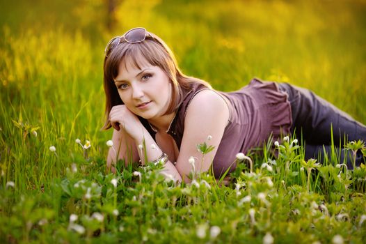 Beautiful woman enjoying daisy field, nice female lying down in the meadow of flowers, pretty girl relaxing outdoor, having fun, happy young lady and spring green nature, harmony and freedom concept 