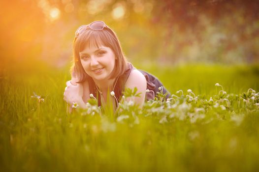 Young pretty woman lying on the grass at summer sunset. Natural happiness, fun and harmony. 