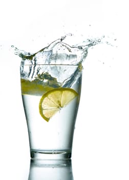 Three lemons are falling into the glass of water.